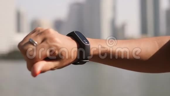 在公园开始有氧运动前女性在智能健身跟踪观察屏幕上进行手指敲击4KSlomotion视频的预览图