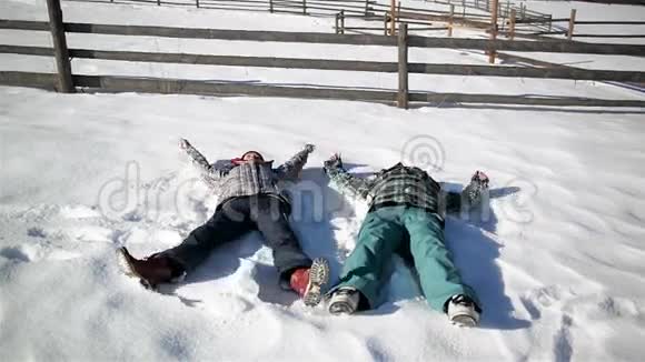 幸福的夫妻就是让雪天使在阳光明媚的温暖日子里躺在地上男人和女人有乐趣视频的预览图