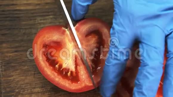 在餐馆的厨房里用手套做饭要切一半的番茄视频的预览图