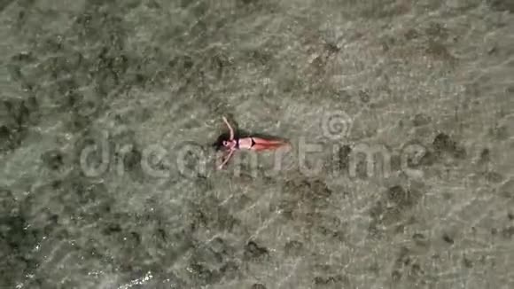 空中美丽的年轻女子游泳躺在清澈的海面上高清慢速运动科尔瓶装海滩视频的预览图