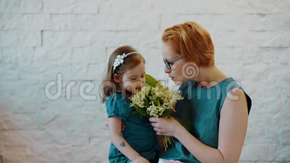 妈妈和小女儿闻着美丽的花朵视频的预览图