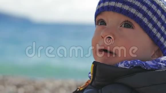 一个戴着冬帽的漂亮小孩子在沙滩上玩玩具视频的预览图