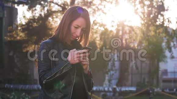 迷人的年轻女孩站在繁忙的嗡嗡声城市中的夏季日落阳光灿烂的年轻女子视频的预览图