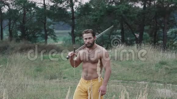 英俊的自由战士带着剑在草原上行走慢慢地视频的预览图