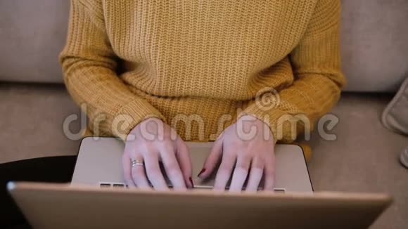 女性的手在笔记本电脑上工作坐在家里的沙发上打字女性持有电脑的Fop视图视频的预览图