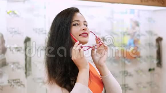 美丽的女人盯着相机一家光学商店里戴眼镜的微笑女顾客的画像视频的预览图