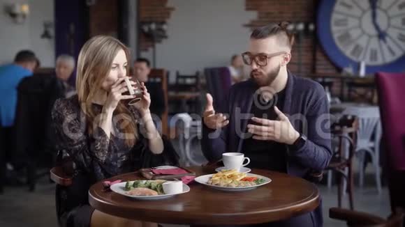 快乐的一对男人和女人坐在自助餐厅的餐桌上一起享用食物和饮料视频的预览图