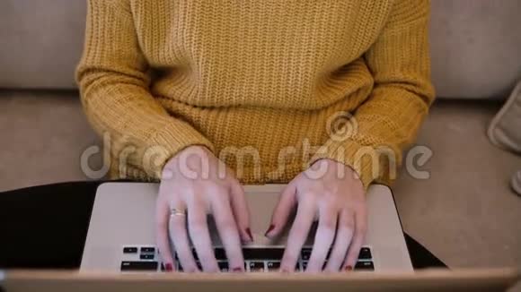 顶部的女性手在笔记本电脑上工作坐在家里的沙发上打字视频的预览图