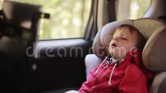 可爱的小男孩嘴张开坐在靠近窗户的汽车椅子上累的孩子在车里视频的预览图