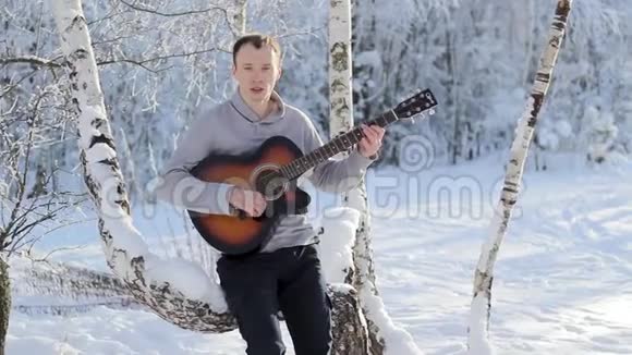 在白雪森林里弹吉他的年轻人视频的预览图