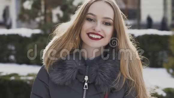 迷人的女孩在冬天的街道上对着镜头微笑慢慢地视频的预览图