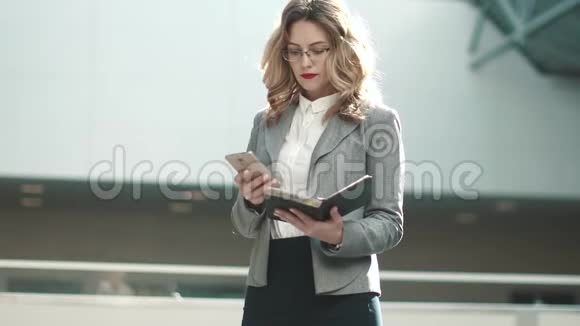 商务女性正在看她笔记本上的笔记在办公楼大厅穿灰色夹克的女孩视频的预览图