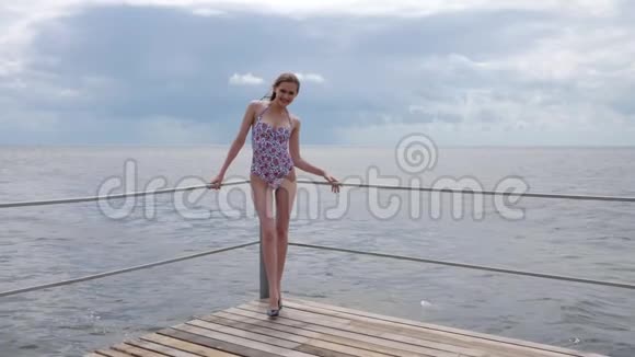 身材窈窕的女人到堤岸苗条的女孩穿着海边泳衣幸福的女人站在码头上视频的预览图