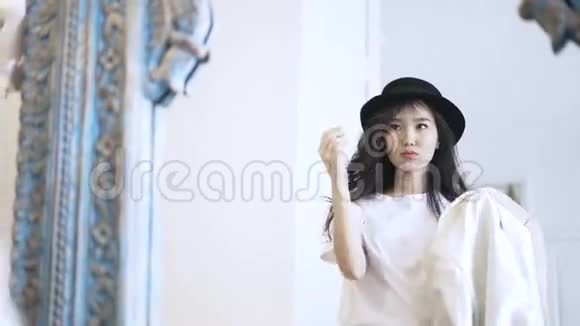 一位戴着帽子的亚洲时尚视频在商店里试穿外套视频的预览图
