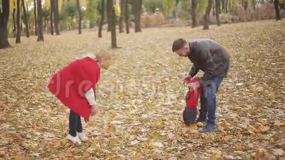 秋天在公园里散步的美丽家庭一个小孩学会和他的父母一起走路视频的预览图