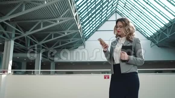 商业女性使用智能手机的肖像商务中心宽敞的大厅里穿商务服的女孩视频的预览图