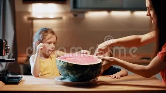 母亲切西瓜女儿和儿子坐在桌子旁咬了一口兄妹吃水果视频的预览图