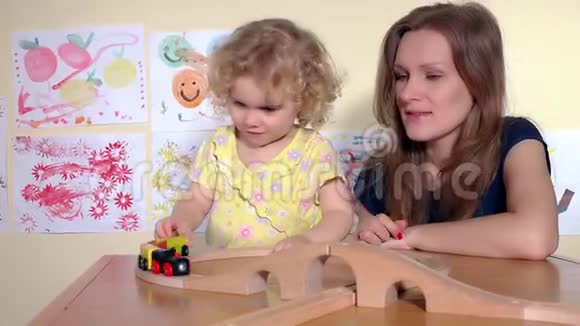 金发可爱的女孩和她的妈妈玩玩具火车拍手视频的预览图