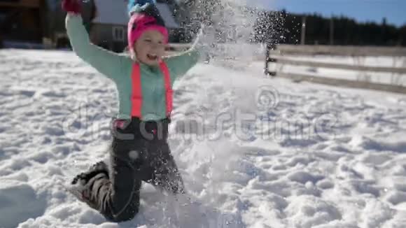 在温暖的阳光日里不安分的小女孩正在扔雪有乐趣的户外活动女孩子玩冬季游戏视频的预览图