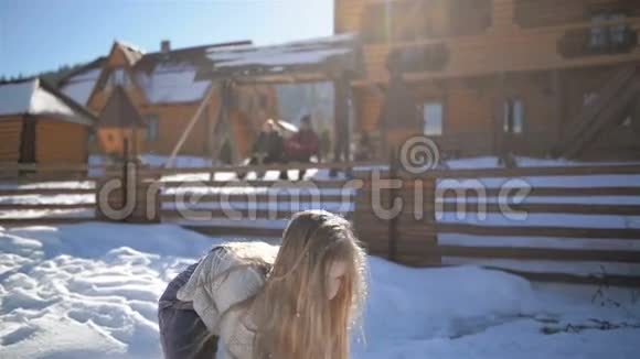 长发可爱的女孩在阳光明媚的日子里扔雪有乐趣的户外活动女孩子正在享受温暖的冬天视频的预览图