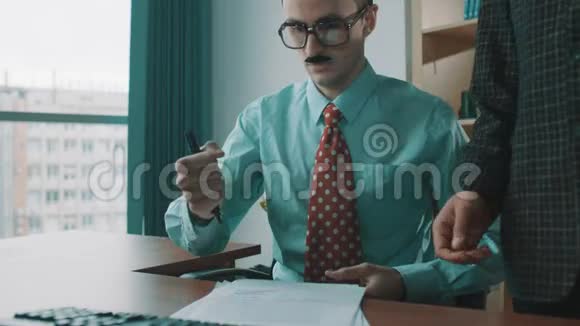 办公室工作人员戴着眼镜假胡子机械地在文件上签名就像机器人一样视频的预览图