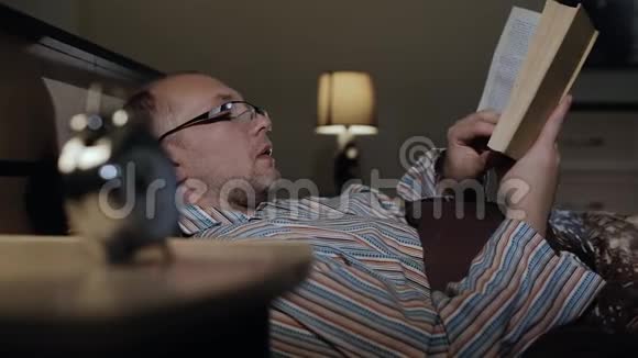 一个戴眼镜的人在睡觉前看书翻阅书页视频的预览图