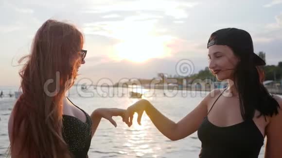 女人把心交在背景大海上女孩看着相机在堤岸上展示心视频的预览图