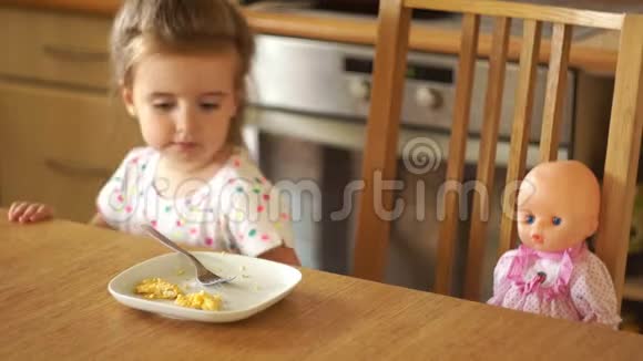 那个女孩正在厨房里喂娃娃她用手拿着食物自己吃妈妈游戏视频的预览图