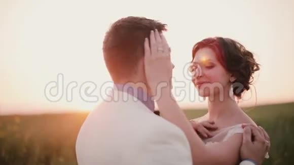 在夏天的婚礼上美丽的情侣在大自然中接吻乡村美妙的日落视频的预览图