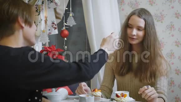 一位年轻的少女棕色头发坐在一家青年咖啡馆里一个年轻人用勺子品尝美味的甜点视频的预览图