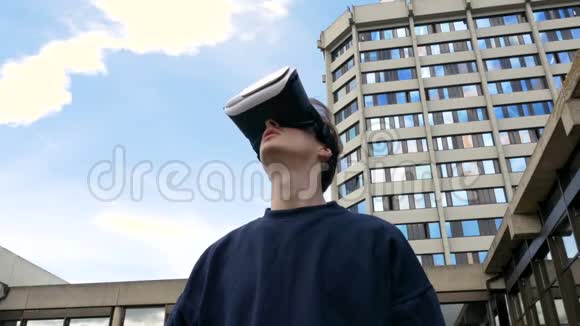 戴着虚拟现实耳机的年轻人朝天空走来视频的预览图