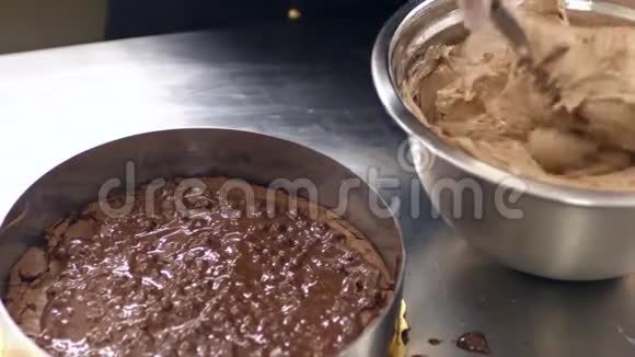 一个糖果师把奶油放在蛋糕上然后把它涂在蛋糕上视频的预览图