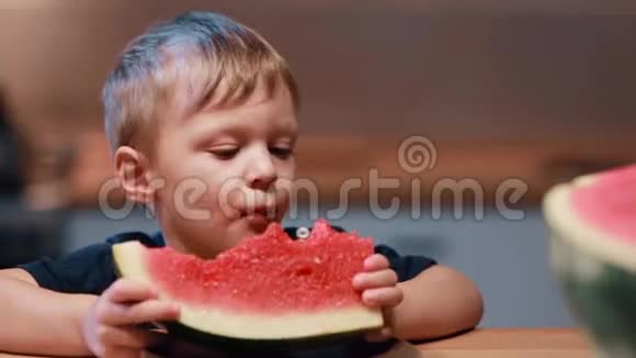 可爱的小男孩坐在厨房的桌子上跳舞的肖像抱着一块吃着西瓜视频的预览图