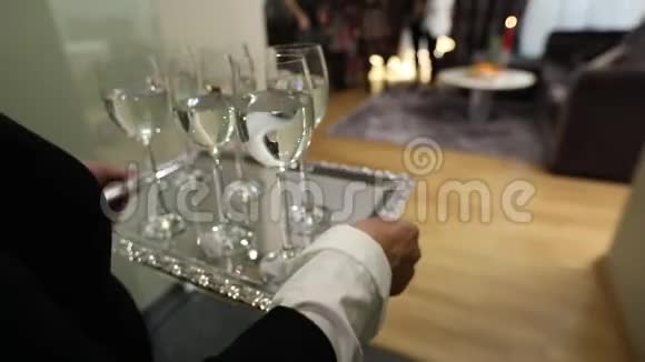 一个女人端着酒杯酒杯上放着饮料酒杯上放着香槟或水放在银盘上视频的预览图