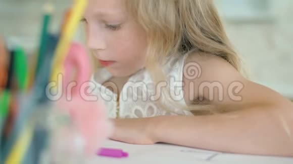 可爱的小女孩坐在桌子旁用铅笔画画视频的预览图