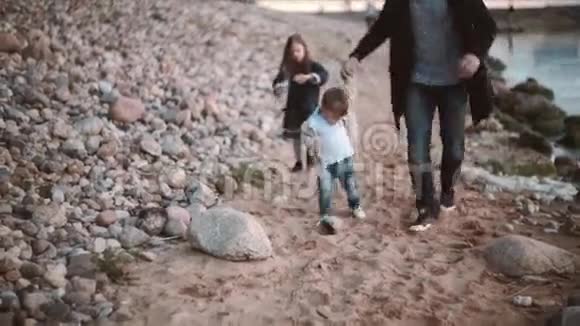 正面看父子走在岸边女儿跑向他们兄弟姐妹花时间和爸爸在一起视频的预览图