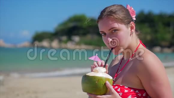 在阳光下喝椰子中的欧洲美丽可爱的布鲁内特年轻女性或快乐女孩的特写镜头视频的预览图