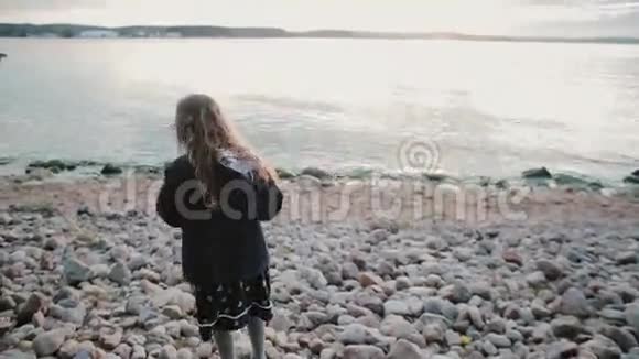 在岸上行走的女孩的后景小女孩在石头上摇摇晃晃地走走向水里视频的预览图