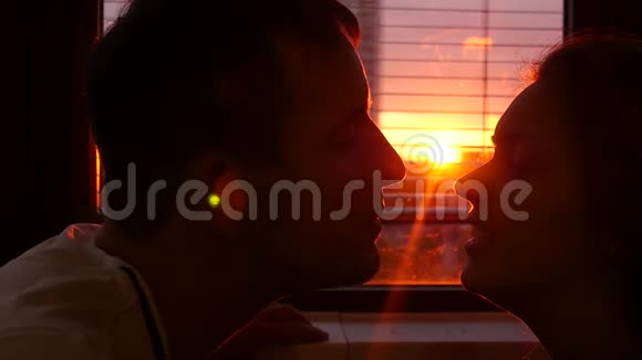 一对相爱的男人和女人在美丽的炽热的夕阳下在家里接吻慢速运动高清1920x1080视频的预览图