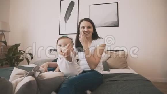 年轻的母亲和可爱的女儿在卧室里玩得很开心慢动作视频的预览图