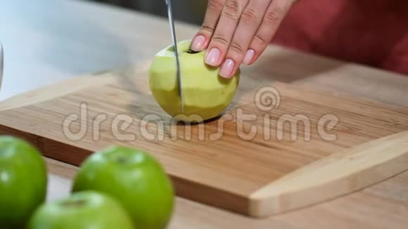 女人用刀子切苹果在厨房的木板上健康的饮食和生活方式视频的预览图