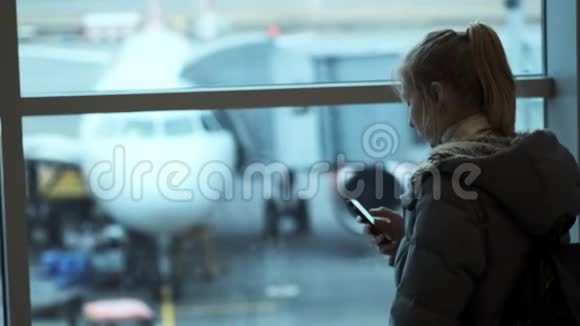 女旅行者等着出发用她的手机一个年轻的女孩写了一条信息等待航班视频的预览图