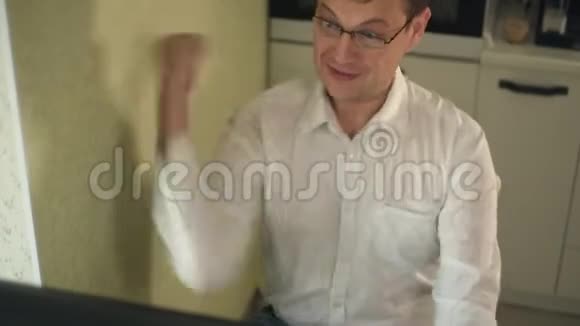 兴奋的尖叫的年轻人看着他的电脑屏幕举起双手胜利视频的预览图