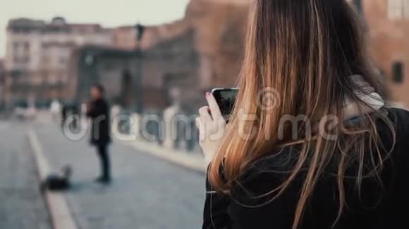在市中心散步的女游客罗马论坛女性在智能手机上拍摄古镇和音乐家的照片视频的预览图