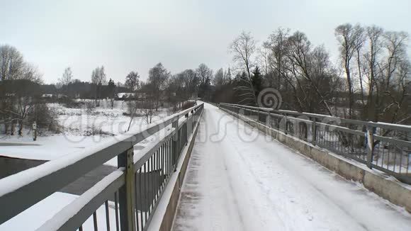 冬季冰雪覆盖的桥梁和冰柱在河水上流动视频的预览图