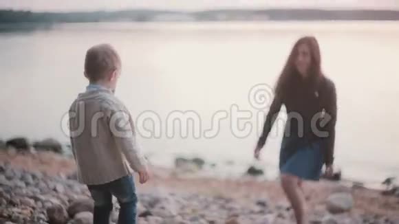 小男孩穿过岩石走向母亲女人在远处等待儿子支持男孩伸出手视频的预览图