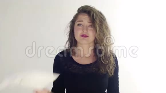 年轻的卷发女子抱着床单带着悲伤的微笑白色的背景视频的预览图