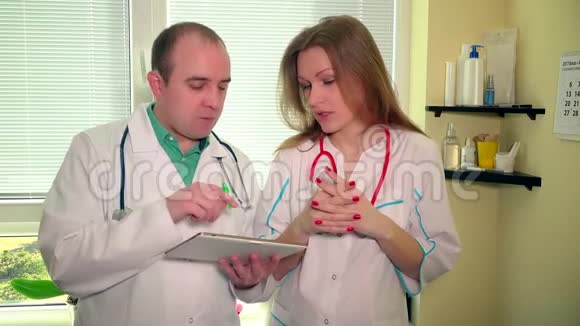 两位医生的同事男性和女性都在争论平板电脑屏幕视频的预览图