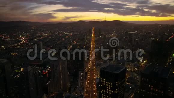 在旧金山的黄昏灯光下在市中心天际线日落的城市景观中在平静的大洋河上空进行了巨大的空中无人机飞行视频的预览图