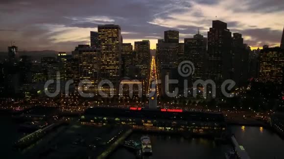 在平静的大洋河上在旧金山傍晚的灯光下在市中心的天际线上在日落的城市景观上进行神奇的空中无人机飞行视频的预览图